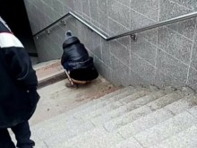 Жена, клекнала на стълбите на софийска метростанция, потресе мрежата (18+)